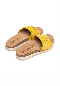 Gelbe Wildleder-Slide-Sandalen mit einem geknoteten Riemendesign. Korkfußbett mit beiger Einfassung und geprägtem Markenlogo auf der Innensohle.