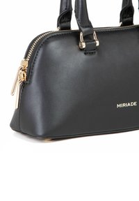 Sort syntetisk læder håndtaske med guld hardware, struktureret design, dobbelte håndtag og lynlåslukning. Har mærkenavnet "MIRIADA" på fronten.