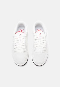 Λευκά αθλητικά παπούτσια από σουέτ και πλέγμα, με επίπεδα κορδόνια, κόκκινες λεπτομέρειες, κυκλικό λογότυπο στη γλώσσα και μαύρη καουτσούκ σόλα.