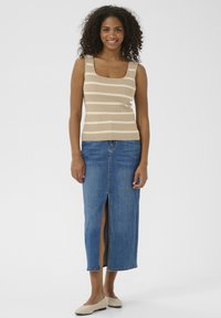 Débardeur beige avec des rayures crémeuses horizontales, associé à une jupe en denim mi-longue avec une fente avant et des ballerines beiges décontractées.