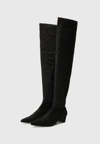 Črne nadkolenske čizme iz mehkega semiša, z usnjenim nosom, nizko blok peto in stranskim zadrgo.