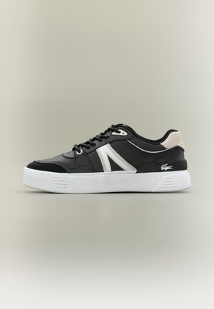 Czarno-białe niskie sneakersy z grubą białą podeszwą, czarnymi sznurowadłami, beżowym akcentem na pięcie i małym logiem krokodyla w pobliżu pięty.