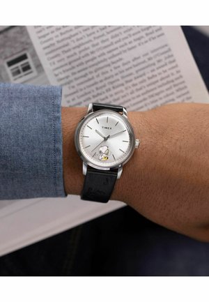 Timex watch with a silver dial, black leather strap featuring music notes, and Snoopy graphic playing a saxophone. Stainless steel case.