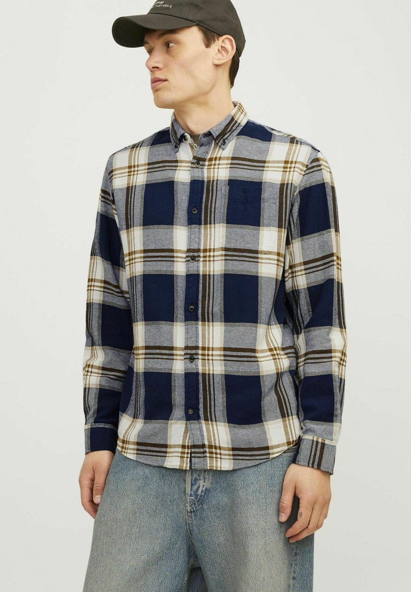 Camisa de cuadros en tonos navy, gris y blanco, con un bolsillo, puños ajustables y un cuello tradicional, elaborada en una tela suave.