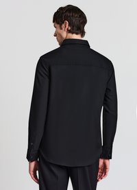 Schwarzes Langarmhemd aus glattem Stoff, mit klassischem Kragen und geknöpften Manschetten, mit abgerundetem Saum und minimalen Details.