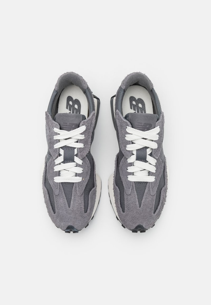 Zapatillas de ante gris y tela con cordones blancos y suela texturizada, que presentan un diseño aerodinámico y una marca mínima en la lengüeta.