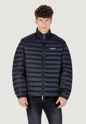 Giacca piumino blu navy con design a cucitura orizzontale, colletto alto, zip frontale e logo del marchio sul lato sinistro del petto.
