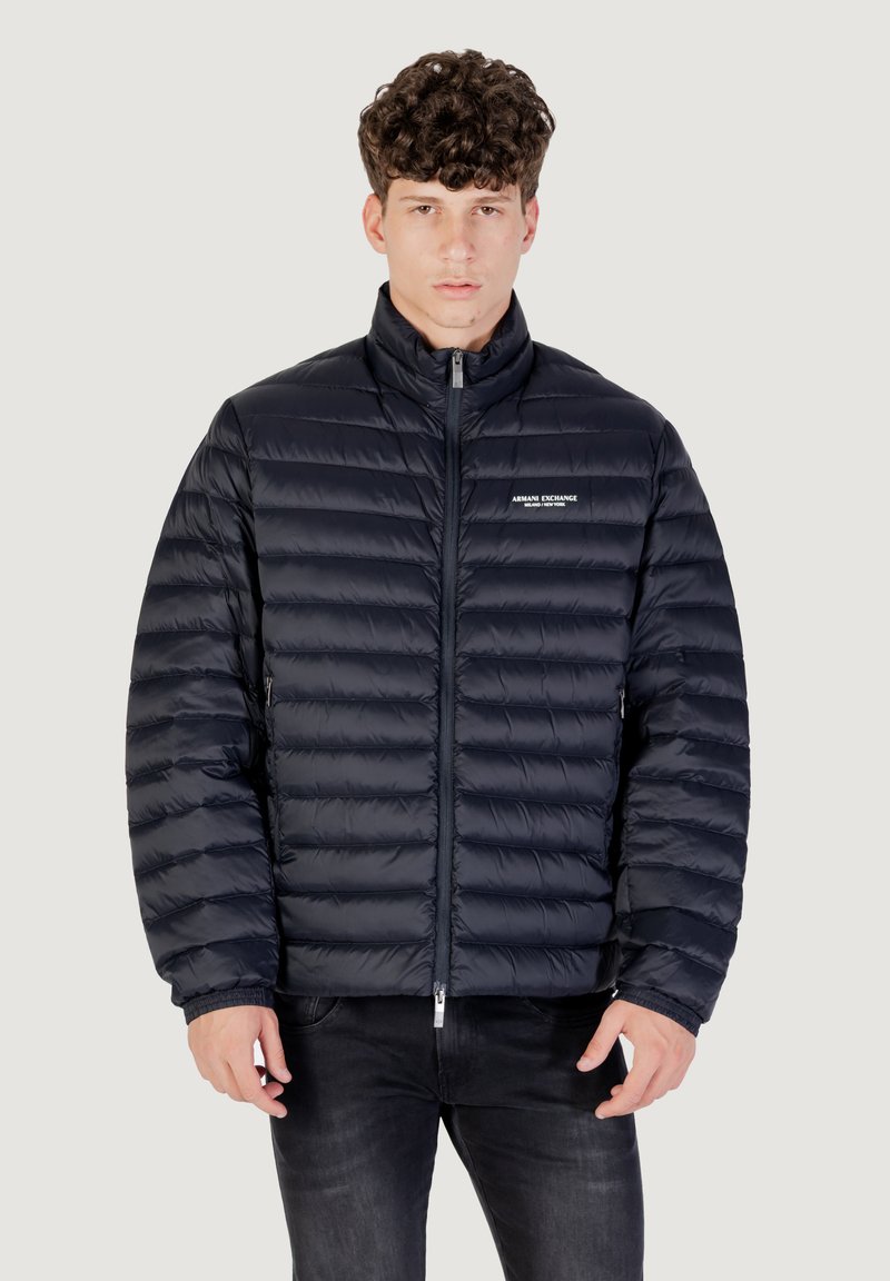 Giacca piumino blu navy con design a cucitura orizzontale, colletto alto, zip frontale e logo del marchio sul lato sinistro del petto.