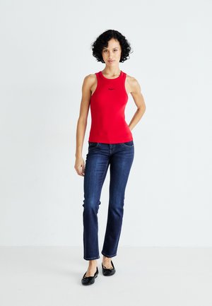 Débardeur rouge à coupe ajustée, associé à un jean droit bleu marine et des ballerines noires. Le débardeur présente des détails de logo noirs.