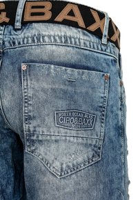Blue denim shorts feature a faded wash, with a prominent back pocket labeled "CIPO&BAXX." The waistband is black with tan lettering.
