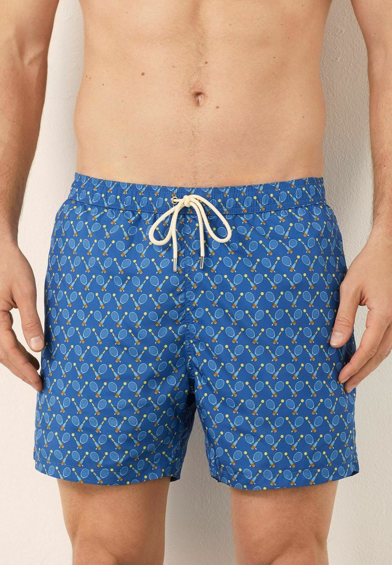 Costume da bagno blu con un motivo a ripetizione di racchette da tennis e palline, dotato di cintura elastica e chiusura con lacci.