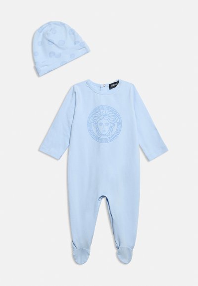 Φωτεινό γαλάζιο βρεφικό φορμάκι με λογότυπο Μέδουσας στο στήθος, συνοδευόμενο από καπέλο στο ίδιο φωτεινό γαλάζιο χρώμα με λεπτό μοτίβο, και τα δύο απλωμένα επίπεδα σε λευκό φόντο.