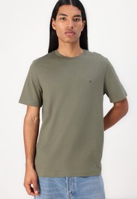 T-shirt verde oliva a maniche corte con collo a giro, caratterizzato da un piccolo logo ricamato sul lato sinistro del petto. Materiale morbido in cotone.