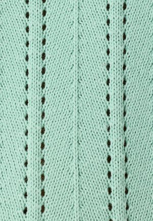 Tessuto verde chiaro lavorato a maglia con fori decorativi verticali e motivi di punti testurizzati alternati che formano degli chevron.