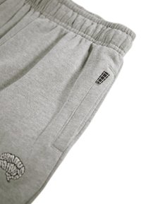 Grijze sweatpants met een elastische tailleband, zijzakken en een klein zwart logo detail op de dij. Zachte stof met een gladde textuur.