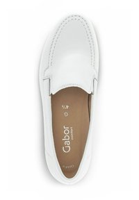 Chaussure blanche sans lacets avec une tige en cuir lisse, des coutures décoratives et un bout arrondi. Semelle intérieure marron clair avec le logo de la marque visible.