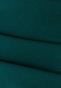 Textured fabric in deep teal, featuring a wavy pattern. Material appears soft and dense, with a slightly crinkled surface.