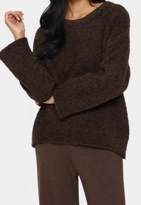 Brun, fluffig stickad tröja med bred båtutskärning, långa ärmar och avslappnad passform, kombinerad med matchande bruna byxor.