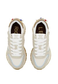 Sneaker beige con lacci bianchi, dettagli di cucitura blu e suole marroni. Presenta il testo "LE RAGAZZE CORRONO PIÙ VELOCE" sulla linguetta e una texture morbida.