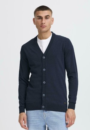 Navy cardigan with a V-neck, button front, ribbed cuffs, and hem. Smooth texture with a subtle sheen, tailored fit.