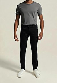 Vaqueros de mezclilla negros combinados con una camiseta gris de cuello redondo y zapatillas blancas. La ropa presenta un diseño ajustado con detalles mínimos.