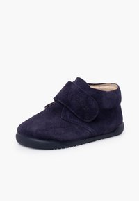 Bottine en daim bleu marine avec une bride velcro, un bout arrondi et une semelle texturée. Doublure intérieure douce pour le confort.