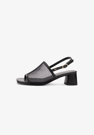 Sandalia de mujer negra con talón descubierto, parte superior de malla, punta abierta, tacón cuadrado y correa con hebilla dorada.