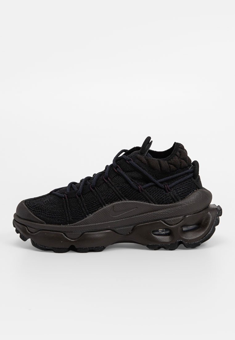 Chaussure de sport noire avec un dessus en maille et des motifs texturés, semelle en caoutchouc, accentuée de détails gris foncé et de coussins d'air visibles.
