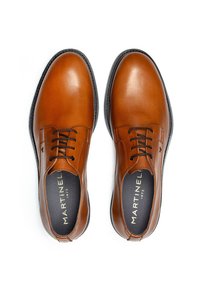 Chaussures habillées en cuir marron avec une texture lisse, bout rond et un laçage à cinq trous. Elles sont dotées d'une semelle en caoutchouc noir et d'un logo de marque.