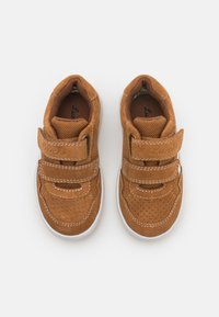 Chaussures en daim marron avec des accents en maille, double strap Velcro, semelle en caoutchouc blanche et détails perforés sur le bout et les côtés.