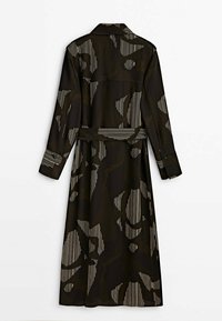 Abito lungo con bottoni in tessuto verde scuro, caratterizzato da motivi astratti in bianco e nero. Presenta maniche lunghe e un bordo in vita da annodare.