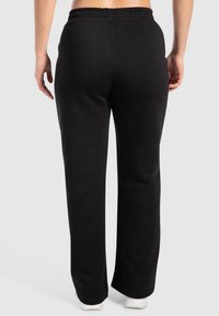 Svarta sweatpants med rak bendesign, elastisk midja och sidofickor, tillverkade av mjukt tyg med en slät textur.