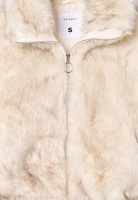 Giacca in pelliccia sintetica con zip di colore crema e texture morbida, caratterizzata da una zip di colore argento e un tirante circolare, etichettata "TERRANOVA", taglia small.