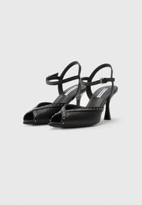 Zwarte high heels sandalen met een open teen ontwerp, voorzien van een gespikkelband, verstelbare enkelband en een glanzende afwerking.