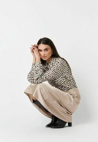 Long-sleeved top with a black and white grid pattern, paired with beige wide-leg pants and black ankle boots. Smooth textures throughout.