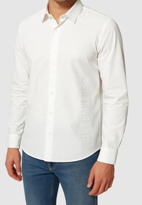 Camicia bianca a maniche lunghe in cotone con colletto button-down, caratterizzata da un logo "BIKKEMBERGS" in rilievo sul lato.
