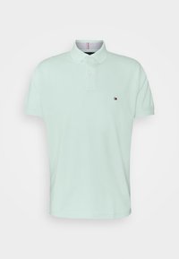 Polo manches courtes vert clair avec col, deux boutons et un petit logo Tommy Hilfiger sur la poitrine gauche.