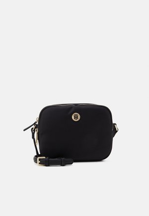 Sacoche en nylon noir avec un matériel doré, fermeture zippée et un emblème à l'avant. Comprend une sangle détachable.