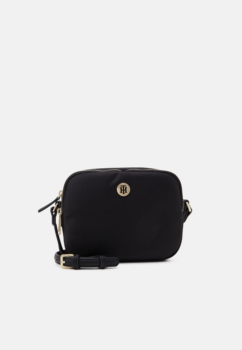 Sacoche en nylon noir avec un matériel doré, fermeture zippée et un emblème à l'avant. Comprend une sangle détachable.