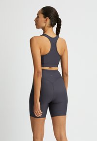 Mörkgrå atletisk set som består av en åtsittande linne med racerbaksdesign och högmidjade shorts med ribbad textur.