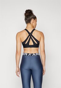 Svart sports-bh med kryssryggstropper, paret med høyt liv navy leggings med en kontrasterende hvit logo-bånd.