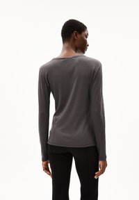 Dunkelgraues Langarmshirt mit rundem Ausschnitt und weichem Material. Die Rückansicht zeigt eine schlanke Passform mit einem dezenten Saum auf Höhe der Taille.