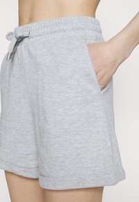 Shorts en coton gris avec une taille élastique et un cordon de serrage, dotés de poches latérales et d'une coupe décontractée. Texture lisse avec un motif subtil en mélange.