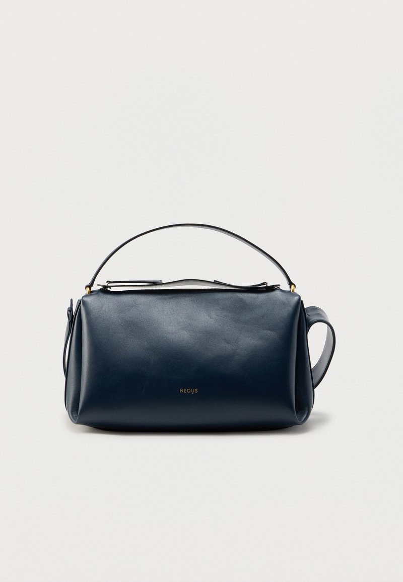 Navy blue leather bag with a smooth texture, cylindrical shape, and a detachable strap. Features a subtle logo in gold.