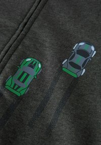 Dunkelgrauer Stoff mit zwei Fahrzeuggrafiken: einem grünen Auto und einem silbernen Auto mit grünen Akzenten, beide aus einer Vogelperspektive dargestellt.