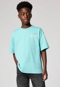 Ljus turkos bomullen t-shirt med en avslappnad passform, med en rund halsringning och "ALLSAINTS" logotyp i vitt framtill. Bärs med mörka jeans.