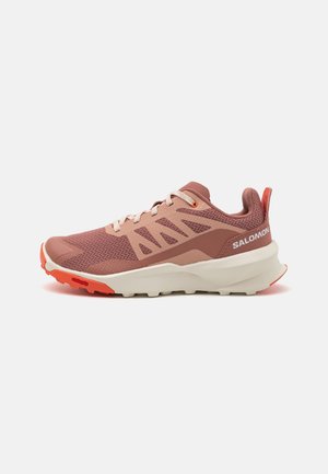 Light pink athletic shoe with mesh and synthetic upper, textured design, white midsole, orange accents, and rugged outsole.