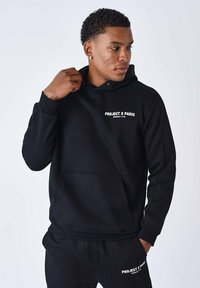 Sudadera negra con bolsillo canguro, que presenta el texto blanco "PROJECT X PARIS MEMBERS' CLUB" en el pecho. Puños y bajo acanalados.