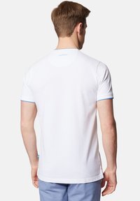 Biała koszulka z krótkim rękawem z niebieskimi akcentami na mankietach i kołnierzyku. Miękki materiał o lekko dopasowanym kroju, logo na górnej części pleców.