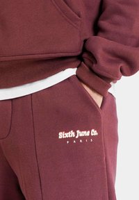 Burgunderfarbener Sweatshirt mit einer weißen Innenschicht, ausgestattet mit einer Tasche, gerippten Bündchen und einer Stickerei mit der Aufschrift "Sixth June Co. PARIS."